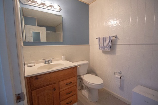 bathroom featuring vanity, tile walls, and toilet