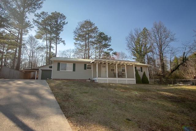 ranch-style house featuring a front yard, an attached garage, fence, and driveway