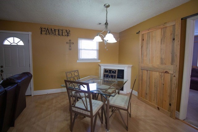 dining room featuring visible vents, a textured ceiling, an inviting chandelier, light wood finished floors, and baseboards