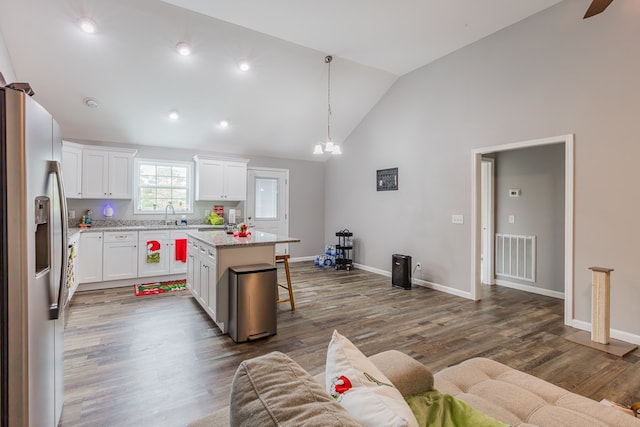 kitchen with white cabinetry, a kitchen island, a kitchen breakfast bar, and stainless steel refrigerator with ice dispenser