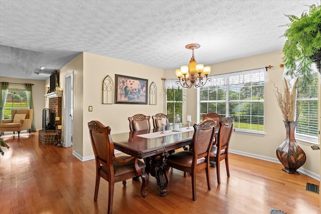 217 Valley Rd, Chatsworth, GA 30705 - dining area featuring wood finished floors, a chandelier, a textured ceiling, and a fireplace
