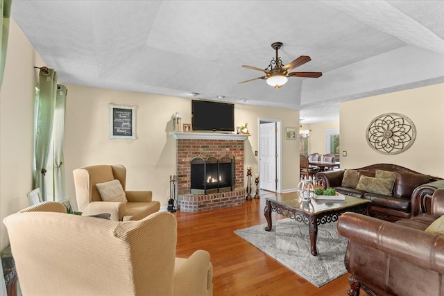 217 Valley Rd, Chatsworth, GA 30705 - living room featuring a tray ceiling, wood finished floors, a ceiling fan, a fireplace, and a chandelier