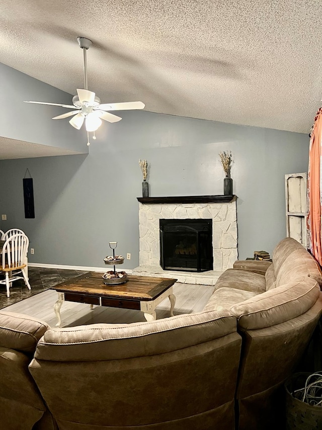 4781 Treetop Ln, Cohutta, GA 30710 - living room featuring a textured ceiling, vaulted ceiling, a ceiling fan, and a stone fireplace