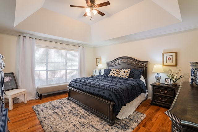 bedroom with ceiling fan, dark hardwood / wood-style flooring, and a raised ceiling