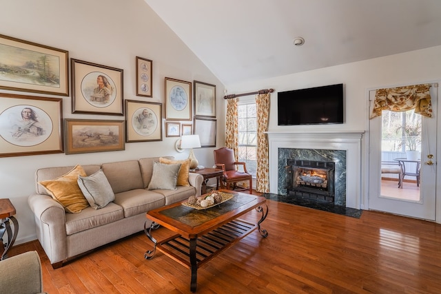 living room featuring plenty of natural light, light wood-type flooring, high vaulted ceiling, and a fireplace