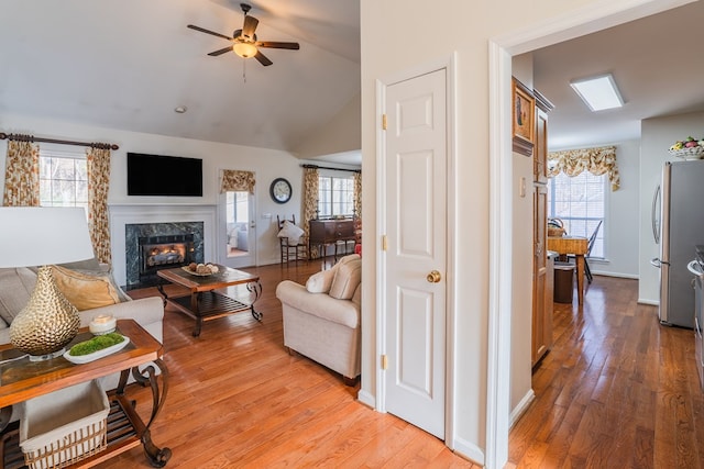 living room featuring a wealth of natural light, light hardwood / wood-style floors, and a premium fireplace