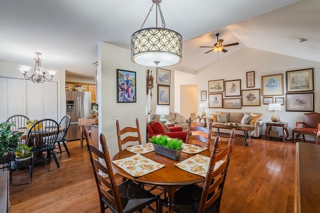 dining space with lofted ceiling, ceiling fan with notable chandelier, and wood-type flooring