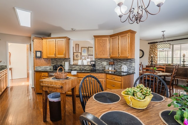 kitchen with pendant lighting, sink, backsplash, hardwood / wood-style floors, and a notable chandelier