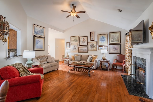 living room featuring lofted ceiling, ceiling fan, a high end fireplace, and wood-type flooring