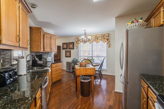 kitchen featuring an inviting chandelier, appliances with stainless steel finishes, dark hardwood / wood-style flooring, pendant lighting, and decorative backsplash