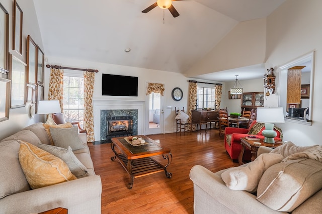 living room featuring ceiling fan, wood-type flooring, a fireplace, and high vaulted ceiling