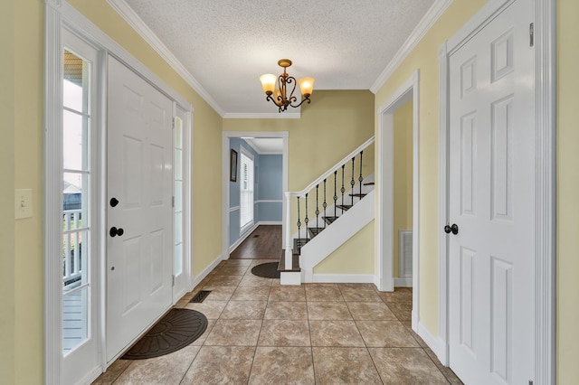 tiled entrance foyer featuring a textured ceiling, crown molding, stairway, and a chandelier