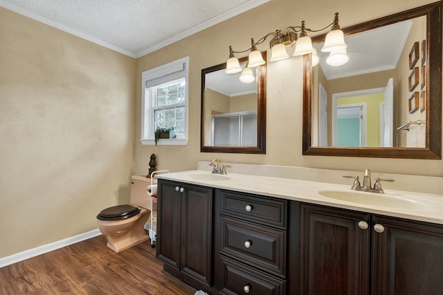 bathroom featuring a sink, toilet, wood finished floors, and ornamental molding