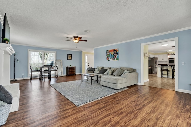 living area featuring ornamental molding, a ceiling fan, dark wood-style flooring, and a textured ceiling