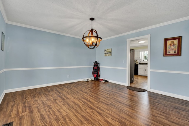 spare room with crown molding, a notable chandelier, wood finished floors, and a textured ceiling