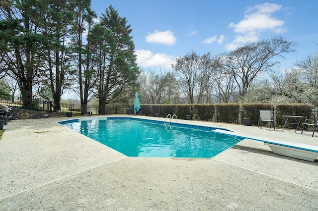 view of swimming pool featuring a diving board, a fenced in pool, a patio, and fence