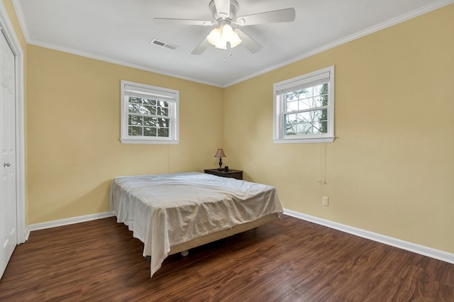 bedroom featuring a ceiling fan, wood finished floors, visible vents, baseboards, and ornamental molding