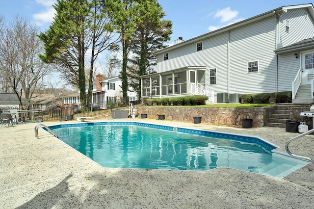 view of pool with a patio, fence, a sunroom, a fenced in pool, and stairs