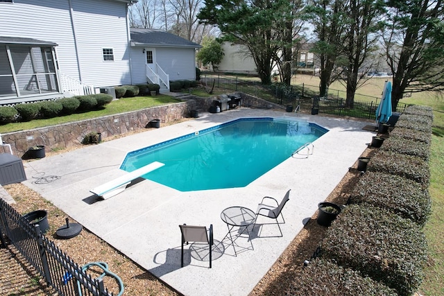 view of swimming pool with a diving board, a fenced in pool, a fenced backyard, and a patio area