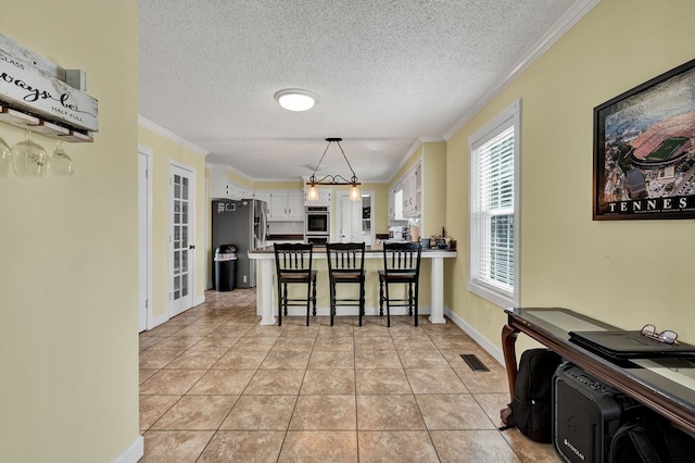 kitchen with visible vents, a peninsula, light tile patterned flooring, ornamental molding, and appliances with stainless steel finishes