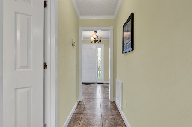 doorway to outside with baseboards, visible vents, a textured ceiling, crown molding, and dark tile patterned floors