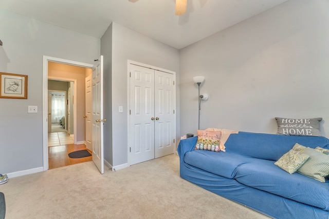 carpeted living room with baseboards and a ceiling fan