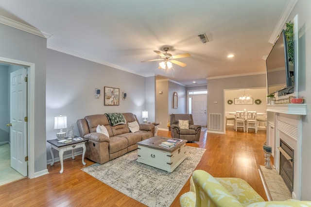 living room with light wood-type flooring, visible vents, baseboards, and crown molding