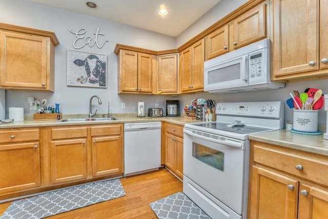 kitchen with white appliances, light wood finished floors, recessed lighting, a sink, and light countertops