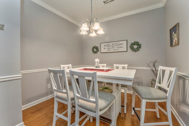 dining space with baseboards, an inviting chandelier, wood finished floors, and crown molding