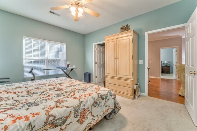 bedroom with visible vents, light colored carpet, a ceiling fan, and baseboards