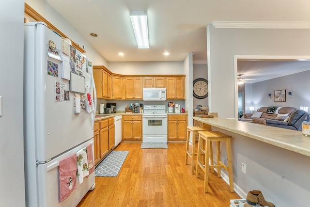 kitchen featuring light wood-type flooring, white appliances, ornamental molding, and light countertops