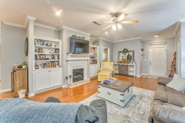 living area with light wood-style flooring, visible vents, and ornamental molding