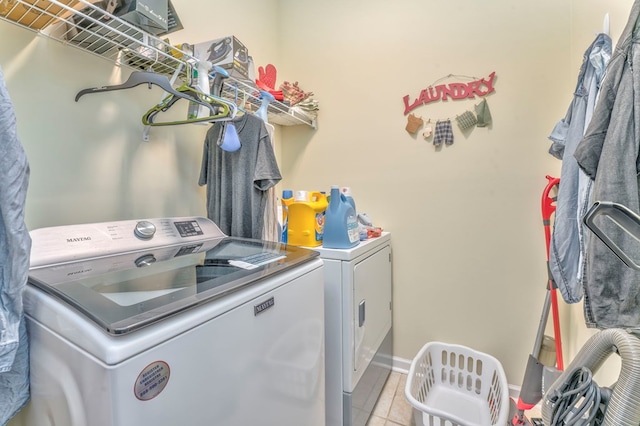 laundry area with light tile patterned floors, laundry area, washing machine and dryer, and baseboards