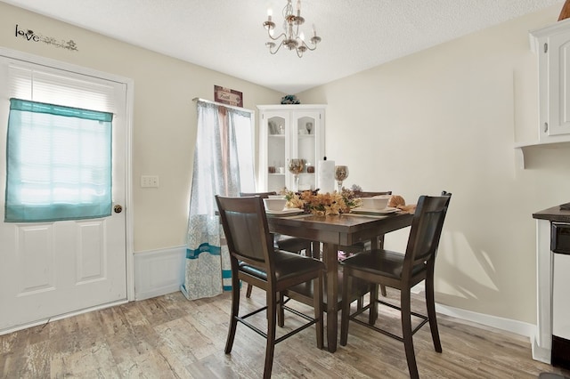 dining area featuring a textured ceiling, a chandelier, and light wood-type flooring