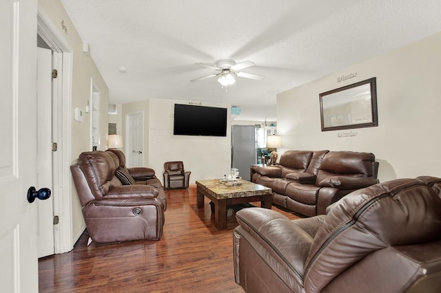 living room featuring ceiling fan, dark hardwood / wood-style flooring, and a textured ceiling