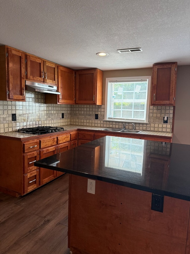 506 Teasley St, Dalton, GA 30721 - kitchen featuring under cabinet range hood, a sink, black gas stovetop, dark wood-type flooring, and brown cabinetry