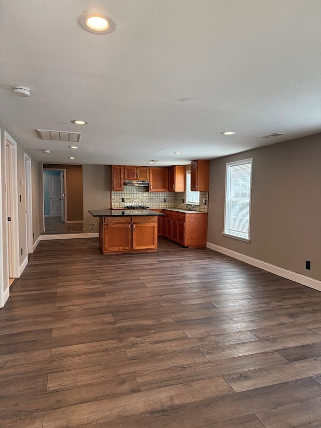 506 Teasley St, Dalton, GA 30721 - kitchen featuring brown cabinets, open floor plan, under cabinet range hood, baseboards, and dark wood finished floors