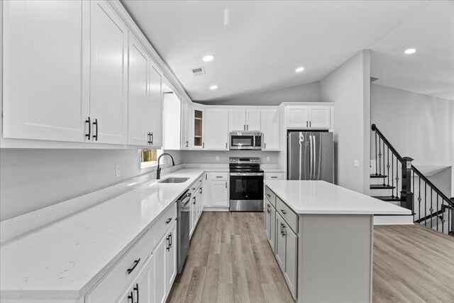 638 Pine Oaks Dr, Tunnel Hill, GA 30755 - kitchen with appliances with stainless steel finishes, a kitchen island, light wood-type flooring, lofted ceiling, and white cabinets