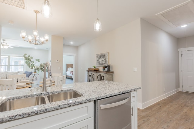 kitchen featuring visible vents, open floor plan, stainless steel dishwasher, white cabinetry, and a sink