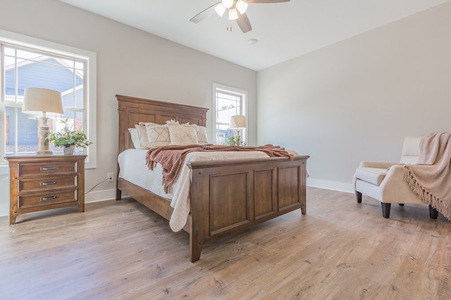 bedroom with light wood-style flooring, a ceiling fan, and baseboards