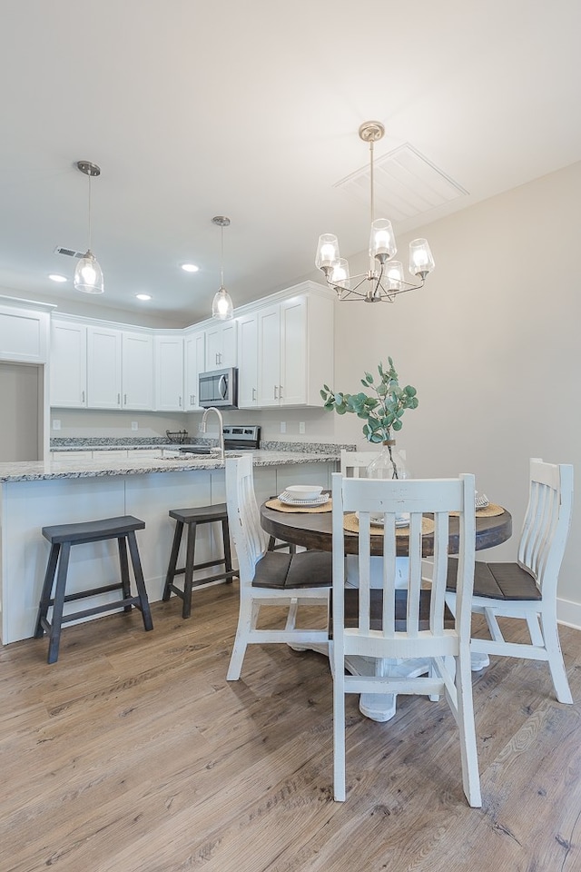 dining area with recessed lighting, light wood finished floors, and a chandelier