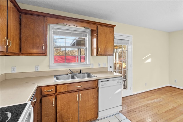 kitchen with sink, a textured ceiling, white appliances, and light hardwood / wood-style flooring