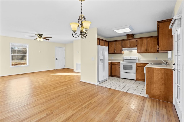 kitchen featuring ceiling fan with notable chandelier, pendant lighting, sink, light wood-type flooring, and white appliances