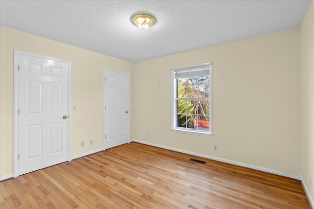 empty room featuring a textured ceiling and light wood-type flooring