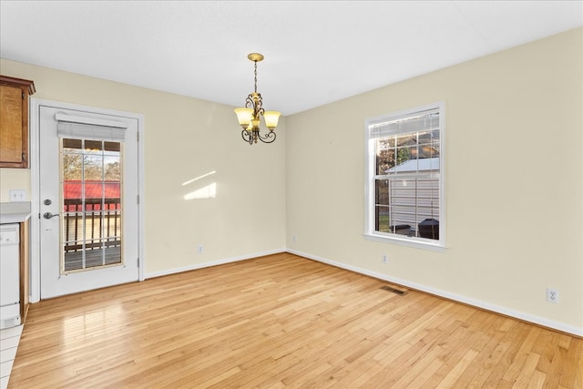 unfurnished dining area with a notable chandelier and light hardwood / wood-style floors