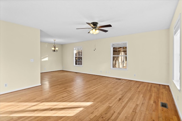 spare room featuring ceiling fan with notable chandelier and light wood-type flooring