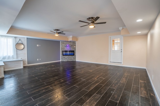 unfurnished living room with ceiling fan, baseboards, wood finished floors, and a fireplace