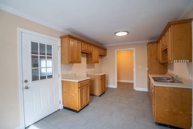 kitchen with light countertops, ornamental molding, baseboards, and a sink