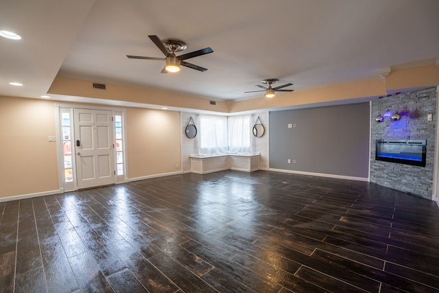 unfurnished living room with a stone fireplace, baseboards, and wood finished floors