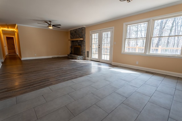 unfurnished living room featuring visible vents, ornamental molding, french doors, a stone fireplace, and baseboards